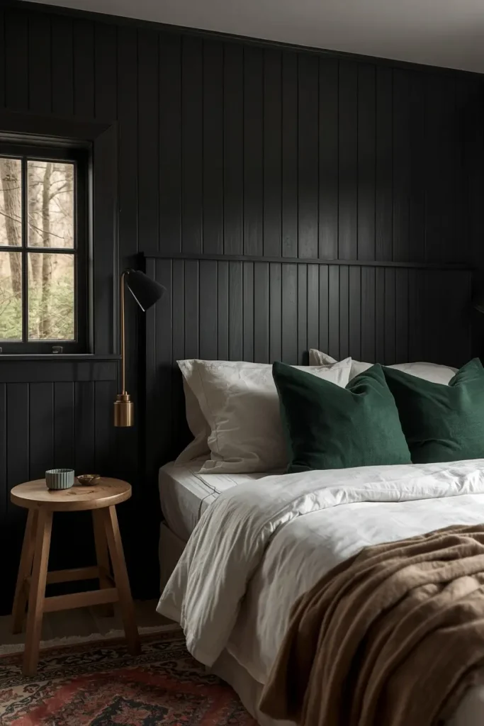 Black board-and-batten headboard wall with forest green pillows and cream bedding in a cottage bedroom