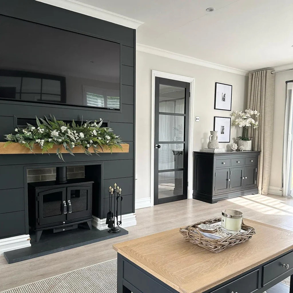 Black shiplap chimney breast with a cast iron stove and an oak beam mantel with eucalyptus