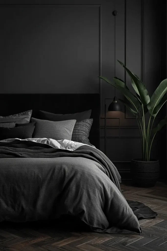 Black headboard on a deep charcoal wall with layered grey bedding and matte black sconces