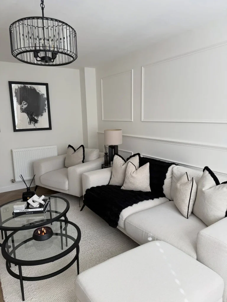 Cream corner sofa with a black faux fur throw, glass nesting tables, and a crystal drum chandelier