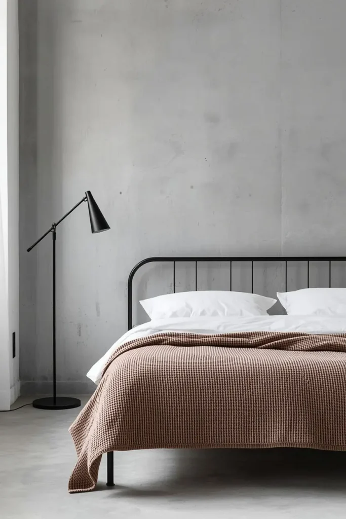 Taupe brown waffle weave blanket over white sheets on a black metal bed in a minimalist loft